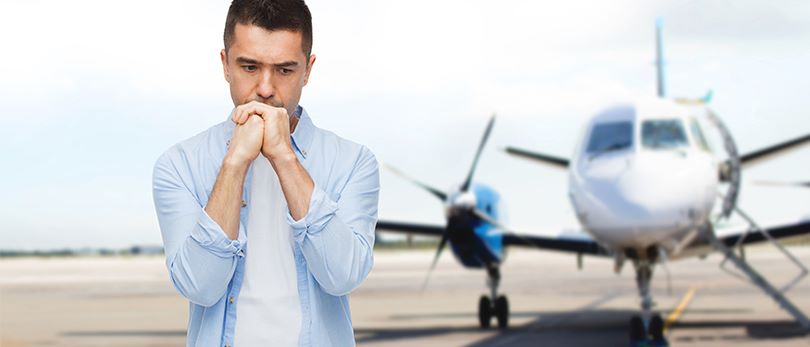 Homme effrayé devant un avion - Symptômes peur de l'avion